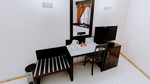 A small, tidy room with a desk, chair, and a television. A mirror hangs on the wall, reflecting a window with curtains. - Panorama Deira (Dubai)