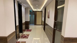 A modern hotel corridor with a shiny tiled floor, wooden paneling, and glass doors. - Panorama Deira (Dubai)