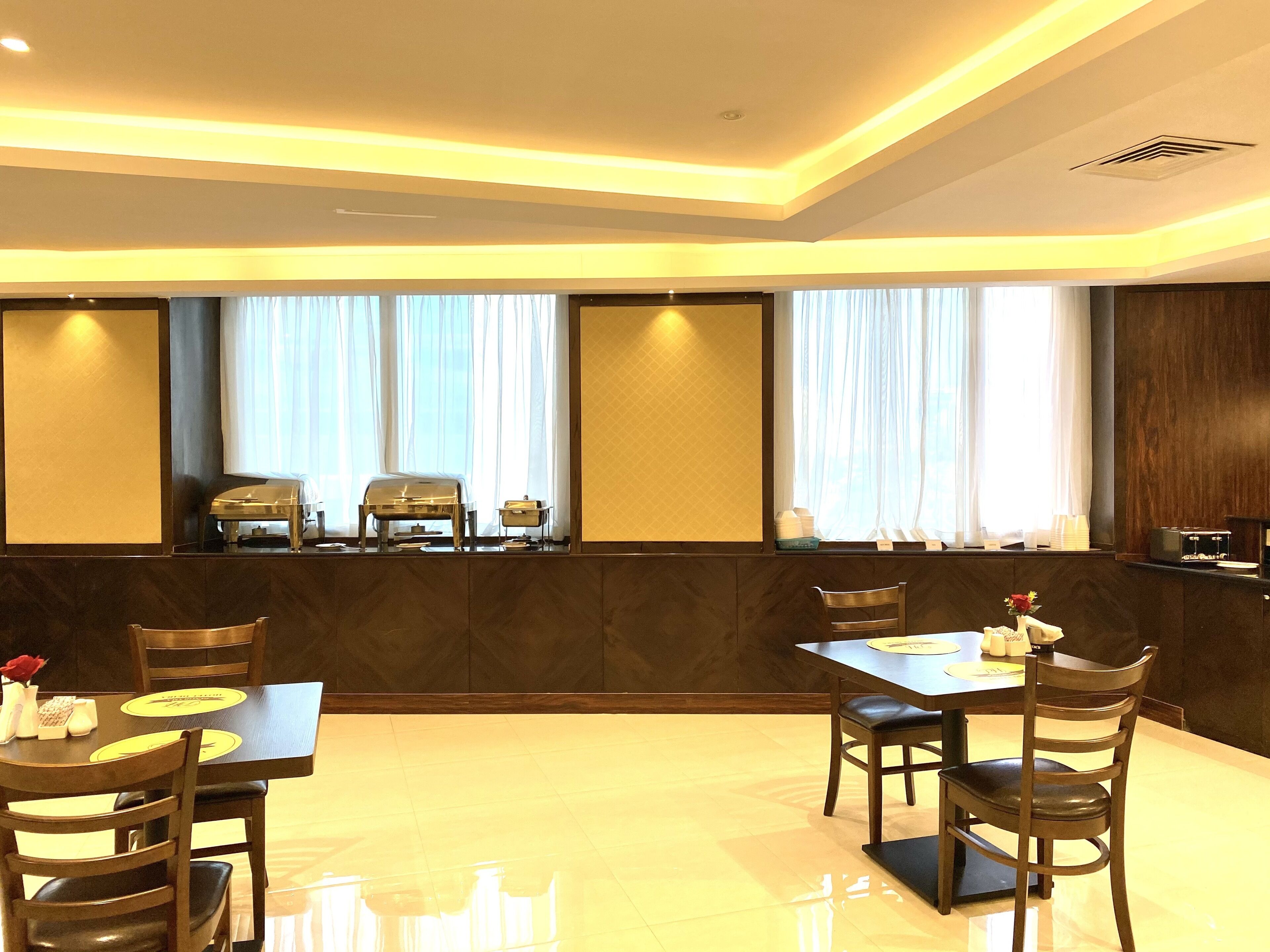 A modern dining area with a long table, several chairs, and a buffet setup.