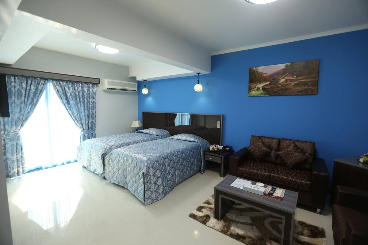 Une chambre à coucher avec un lit, une table de chevet, un canapé et un tableau au mur.