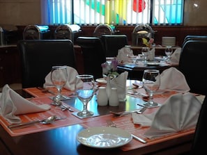 A dining table set with plates, glasses, and cutlery, with a window in the background. - York International (Dubai)