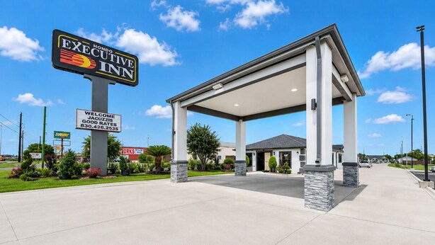 A hotel entrance with a covered waiting area, a sign for Executive Inn, and a Subway restaurant nearby. - Executive Inn of Hondo (Hondo)