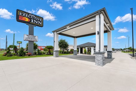 A hotel entrance with a covered waiting area, a sign for Executive Inn, and a Subway restaurant nearby.. Executive Inn of Hondo