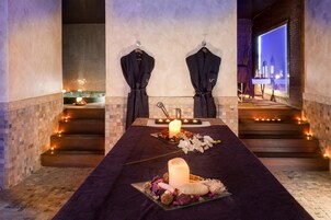 Un cuarto de spa con camilla de masaje, velas y toallas.