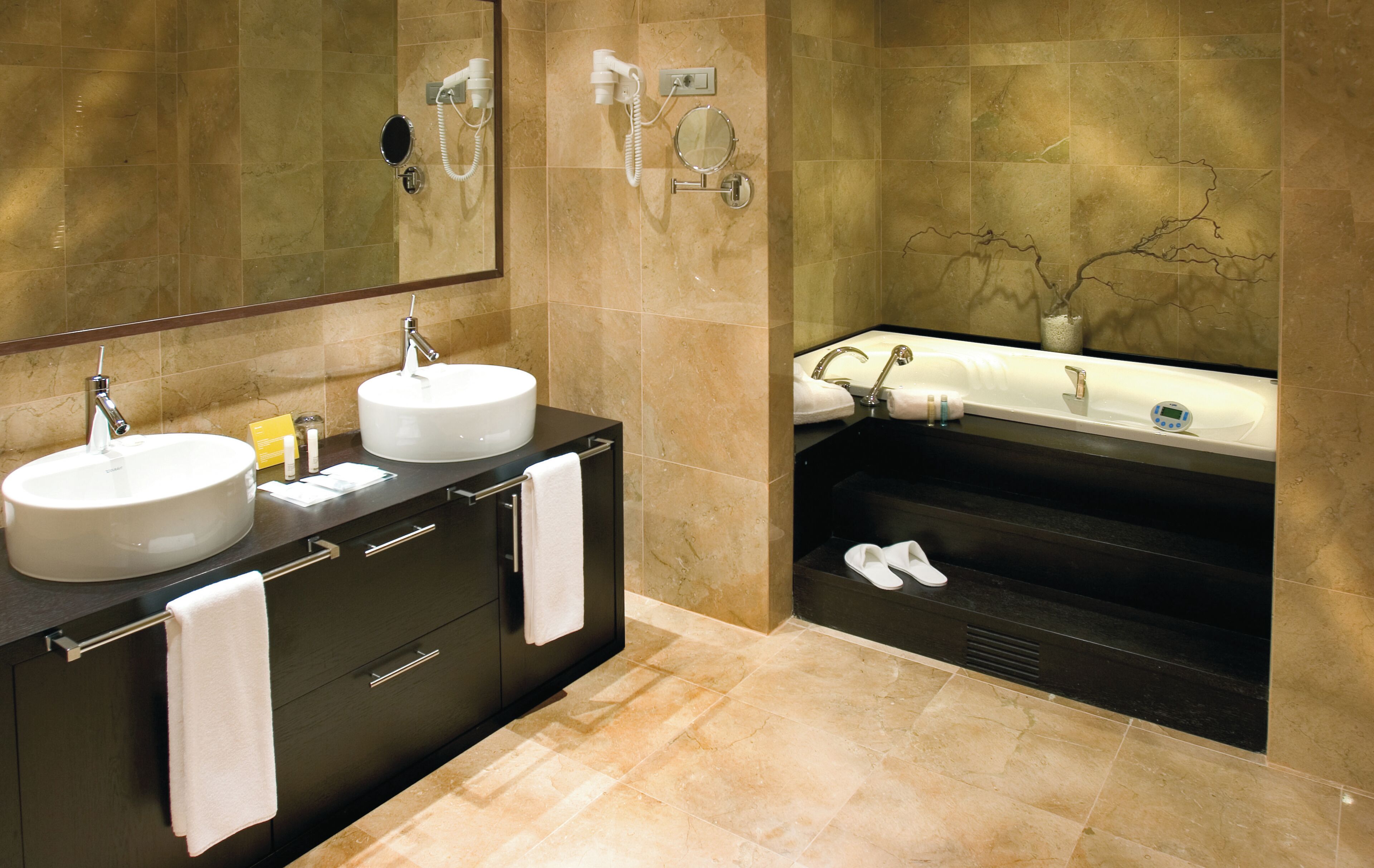 A modern bathroom with two sinks, a bathtub, and a large mirror.