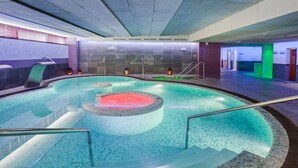 A large indoor swimming pool with a hot tub, tiled walls, and a staircase leading into the pool. - Occidental Aranjuez (Aranjuez)