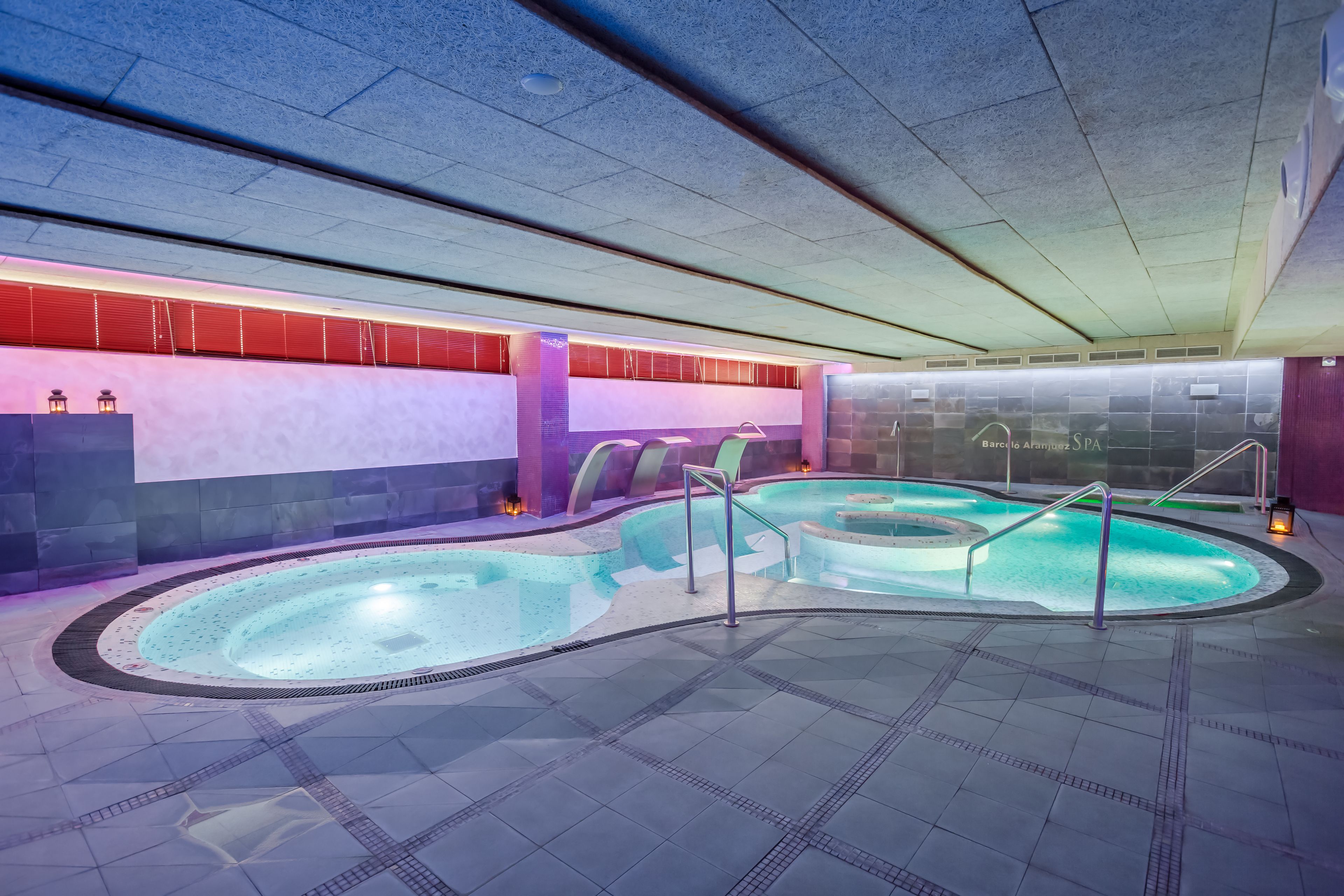 A spa area with a hot tub, tiled flooring, and a wall with a spa logo.