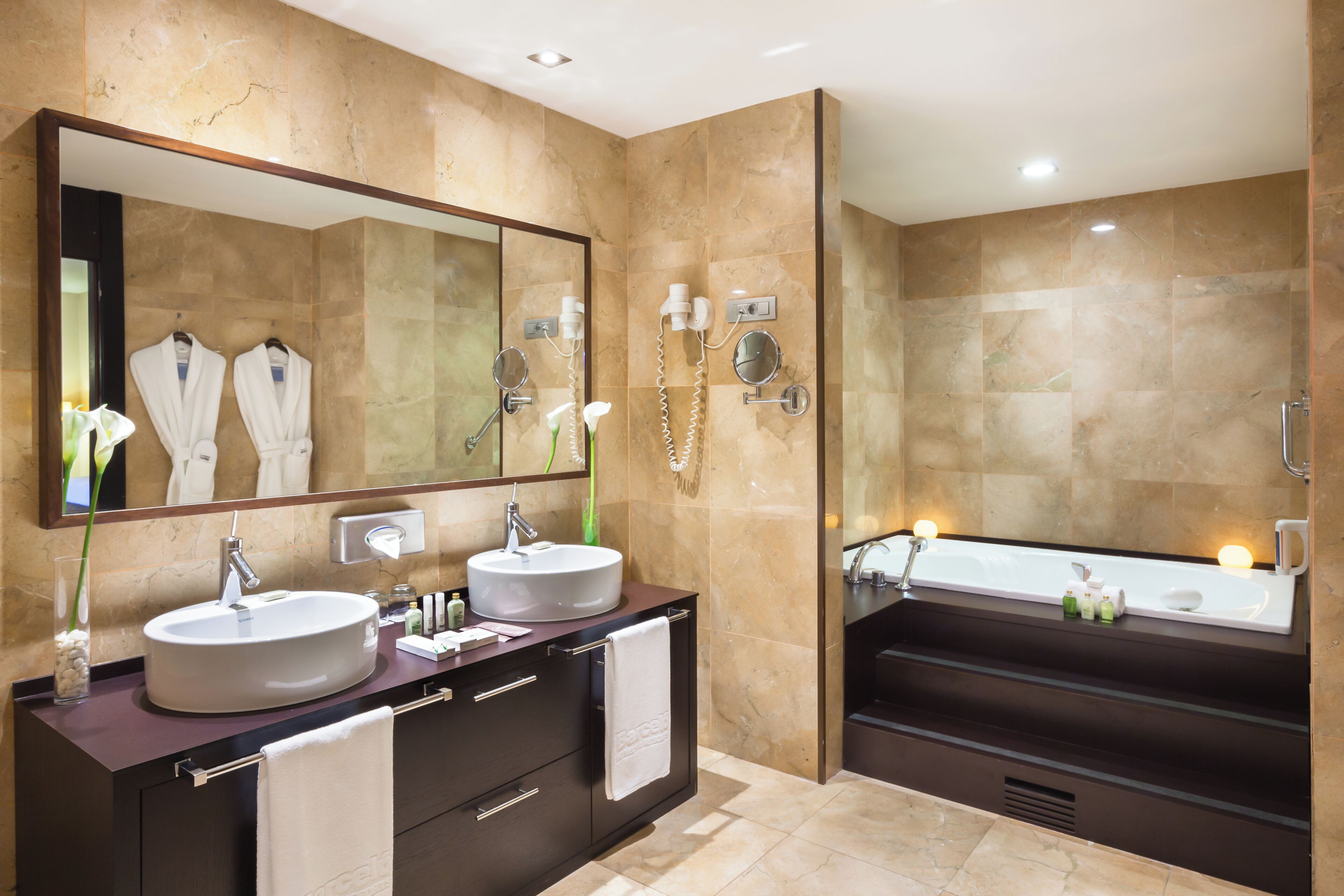 A modern bathroom with two sinks, a large mirror, and a bathtub.