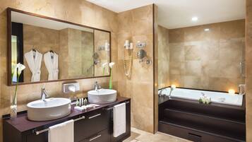 A modern bathroom with two sinks, a large mirror, and a bathtub.