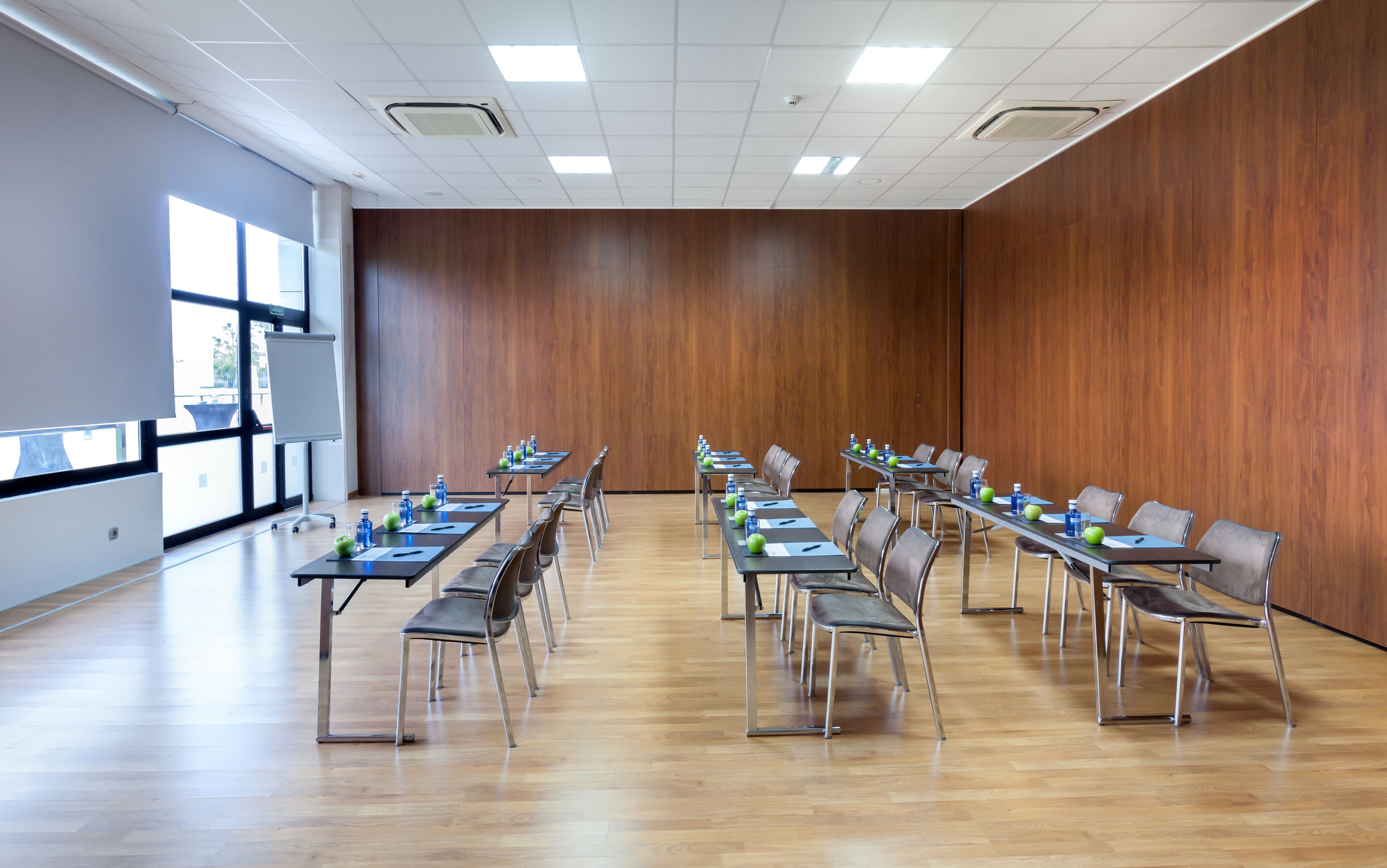 Un salón de conferencias con una larga mesa, sillas y botellas de agua.