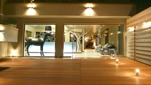 A multi-level building with a wooden deck and a large sculpture of a horse. - Bourtzi Hotel (Skiathos)
