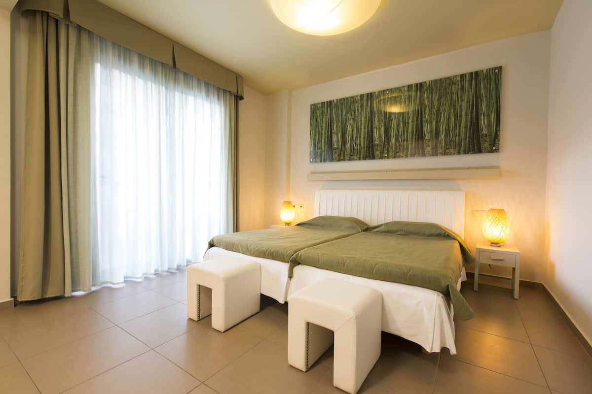 A neatly arranged bedroom with a bed, two bedside tables, and a wall-mounted artwork.