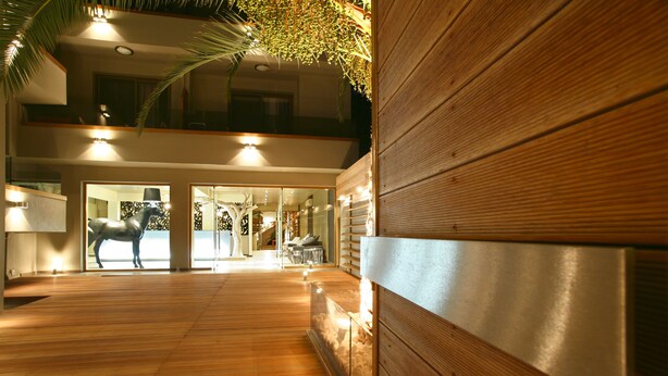 A spacious indoor area with wooden flooring and a glass partition, leading to a well-lit interior space. - Bourtzi Hotel (Skiathos)