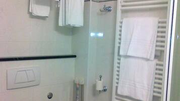 Et badeværelse med toilet, håndklædetørrestativ, brusebad og håndklædevarmer.
