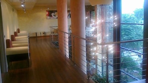 Un hall de hotel con piso de madera, zona de estar y un balcón con barandilla.