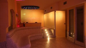 Un vestíbulo de hotel con un mostrador de recepción curvo, una escalera y un separador de vidrio.