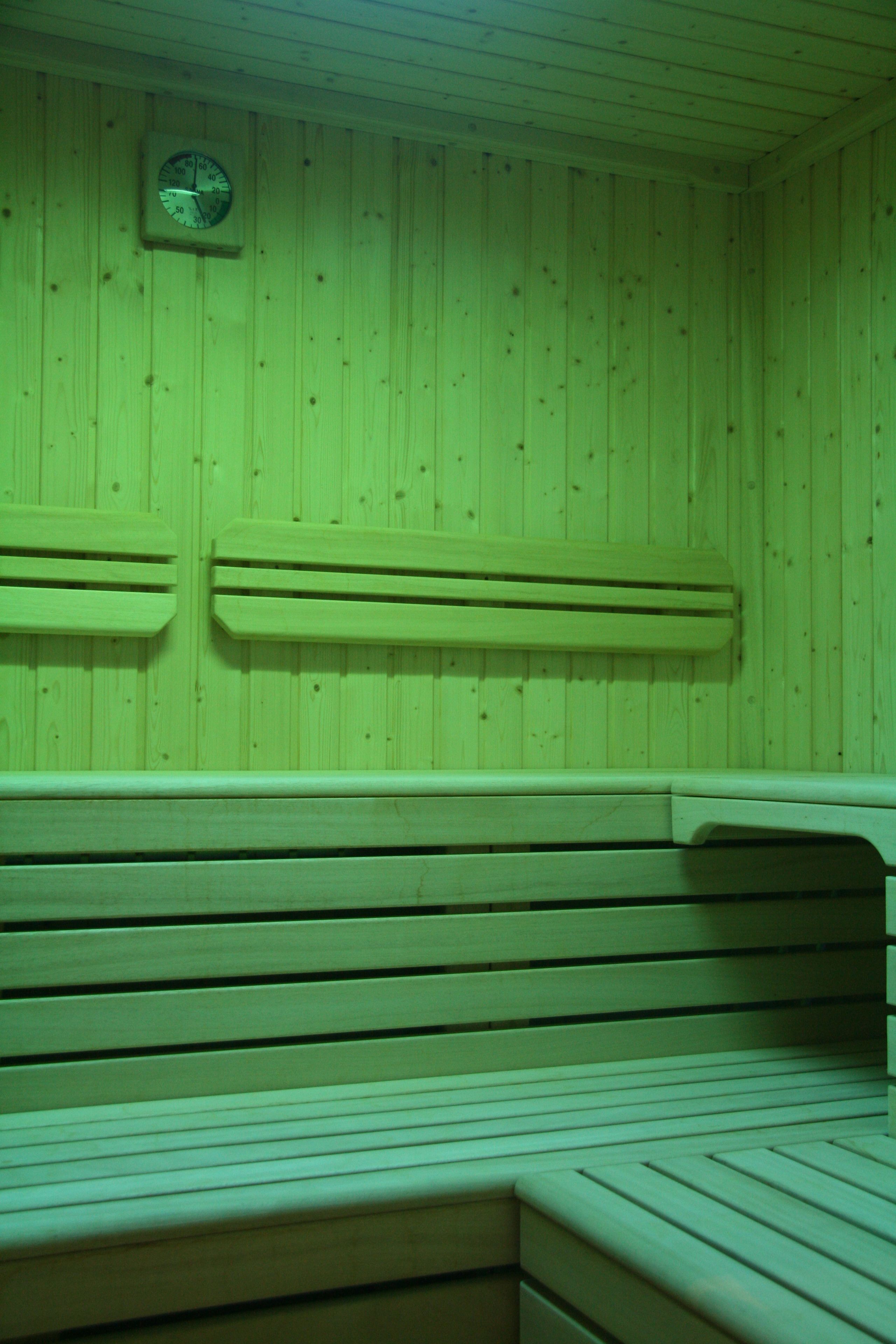 Una sauna con bancos de madera y un reloj visible en la pared.
