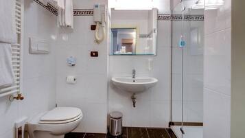 A bathroom with a toilet, sink, and shower.