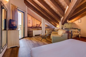 Una camera accogliente con un letto, una scrivania e una sedia. Si vede una finestra con tende, un termosifone e una televisione su un mobile.