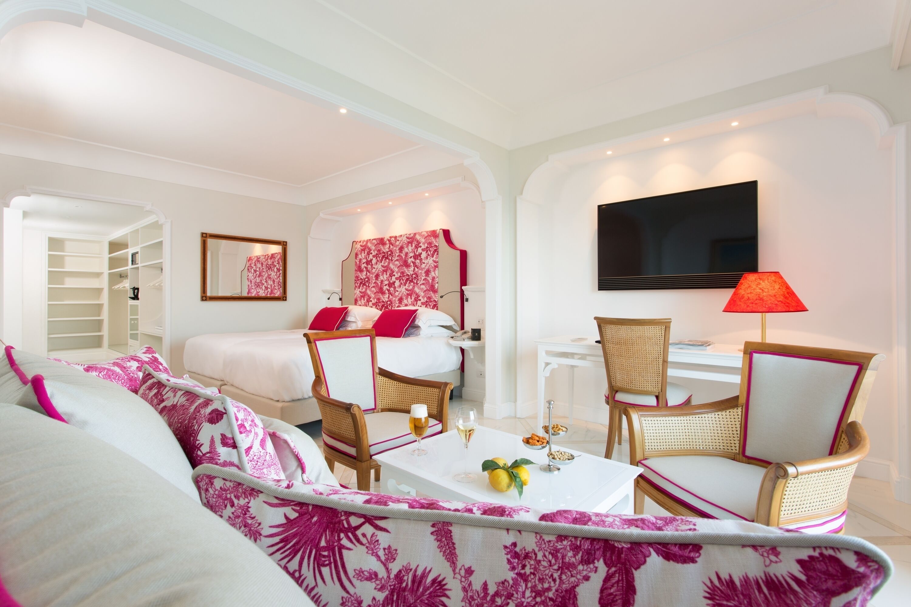Una habitación de hotel con cama, escritorio, televisor, mesa de comedor y sofá.