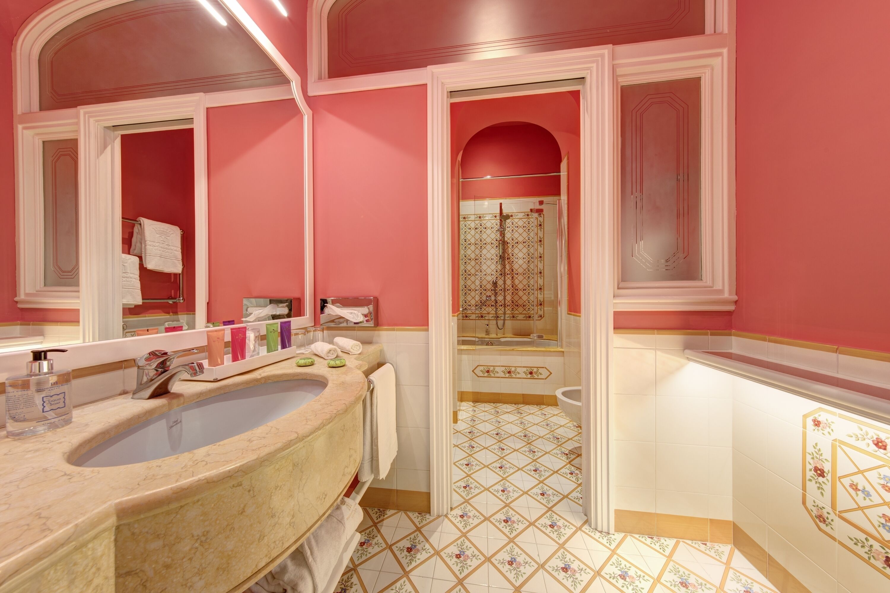 A bathroom with a large marble sink, a double vanity, and a walk-in shower.