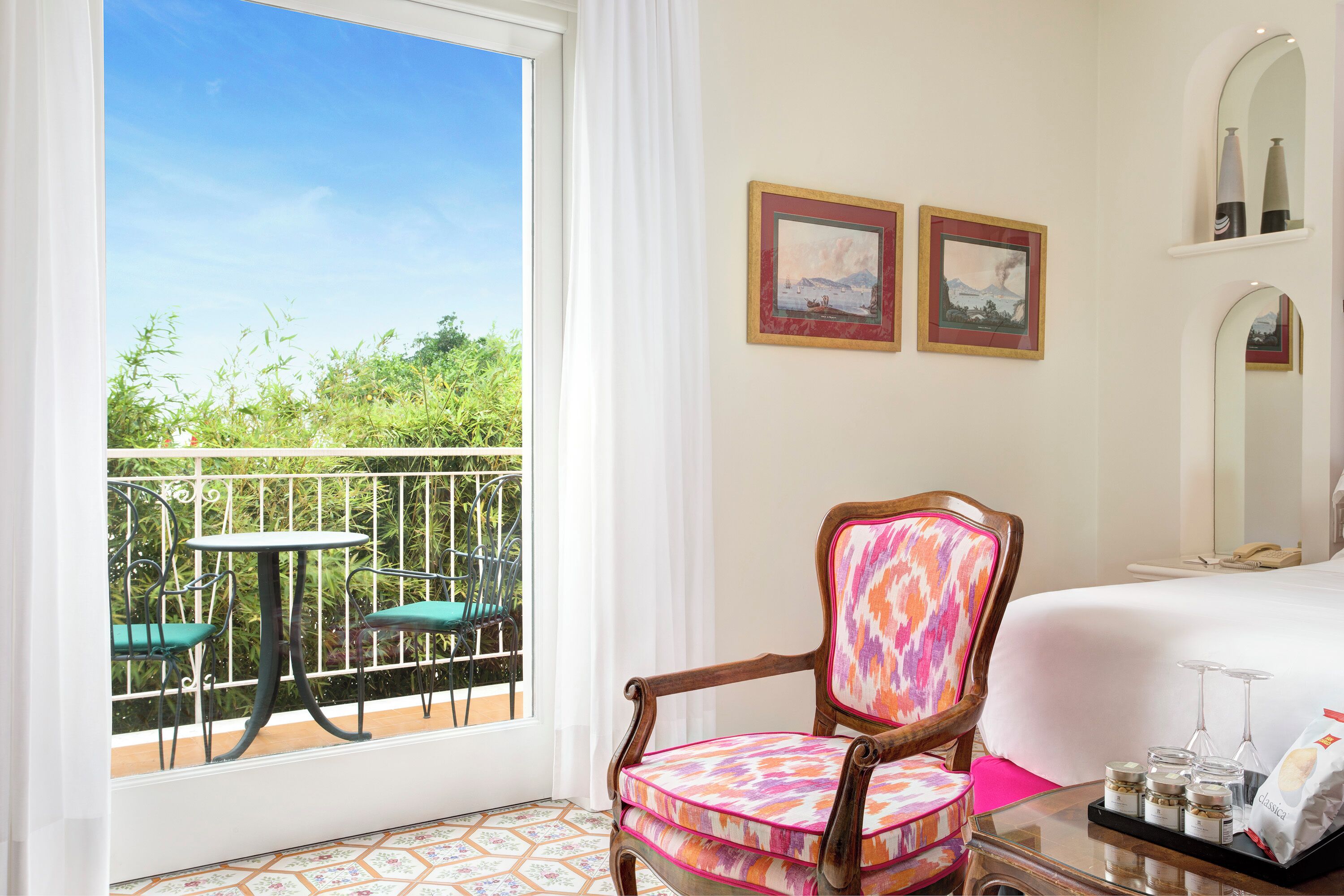 Une chambre d’hôtel avec un balcon, un lit, une chaise et une table sur laquelle se trouvent divers objets.