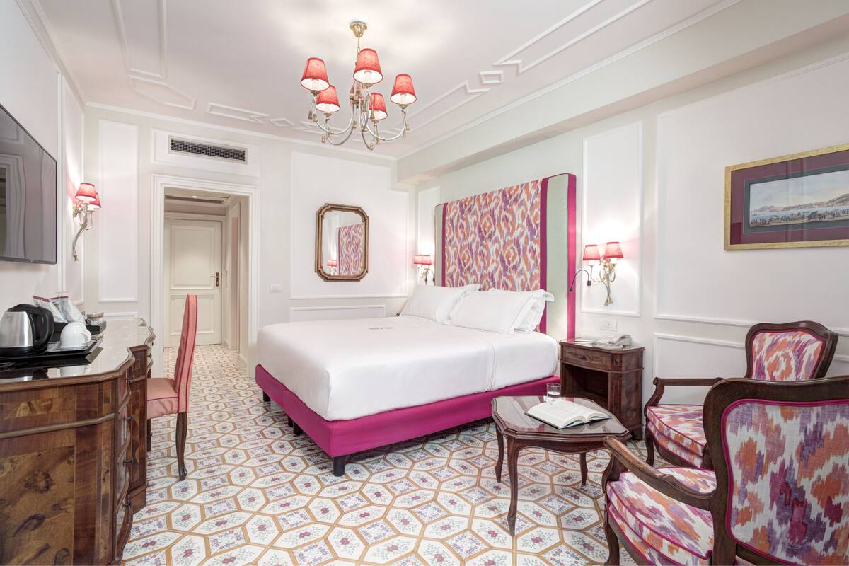 Una habitación de hotel con una cama grande, un escritorio, una silla y un televisor.