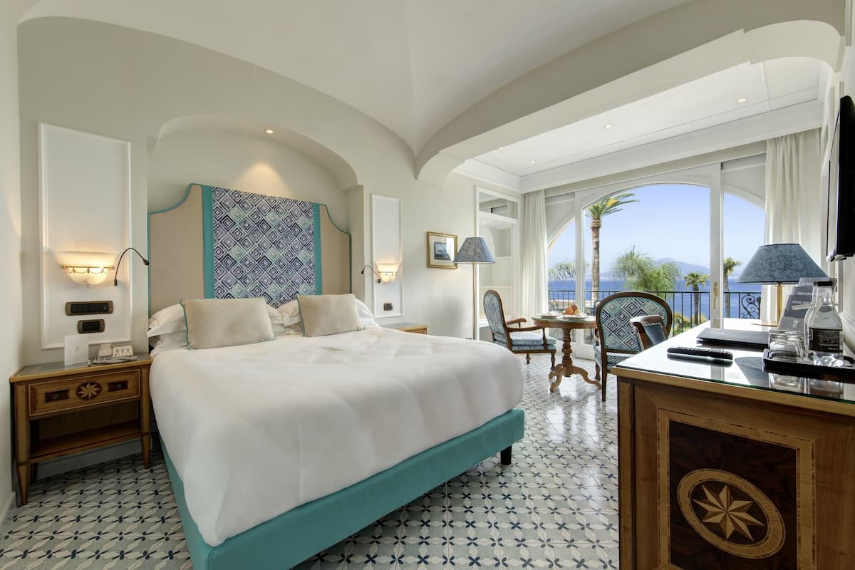 Una habitación de hotel con una cama grande, un escritorio con una silla, un televisor y vista al mar.