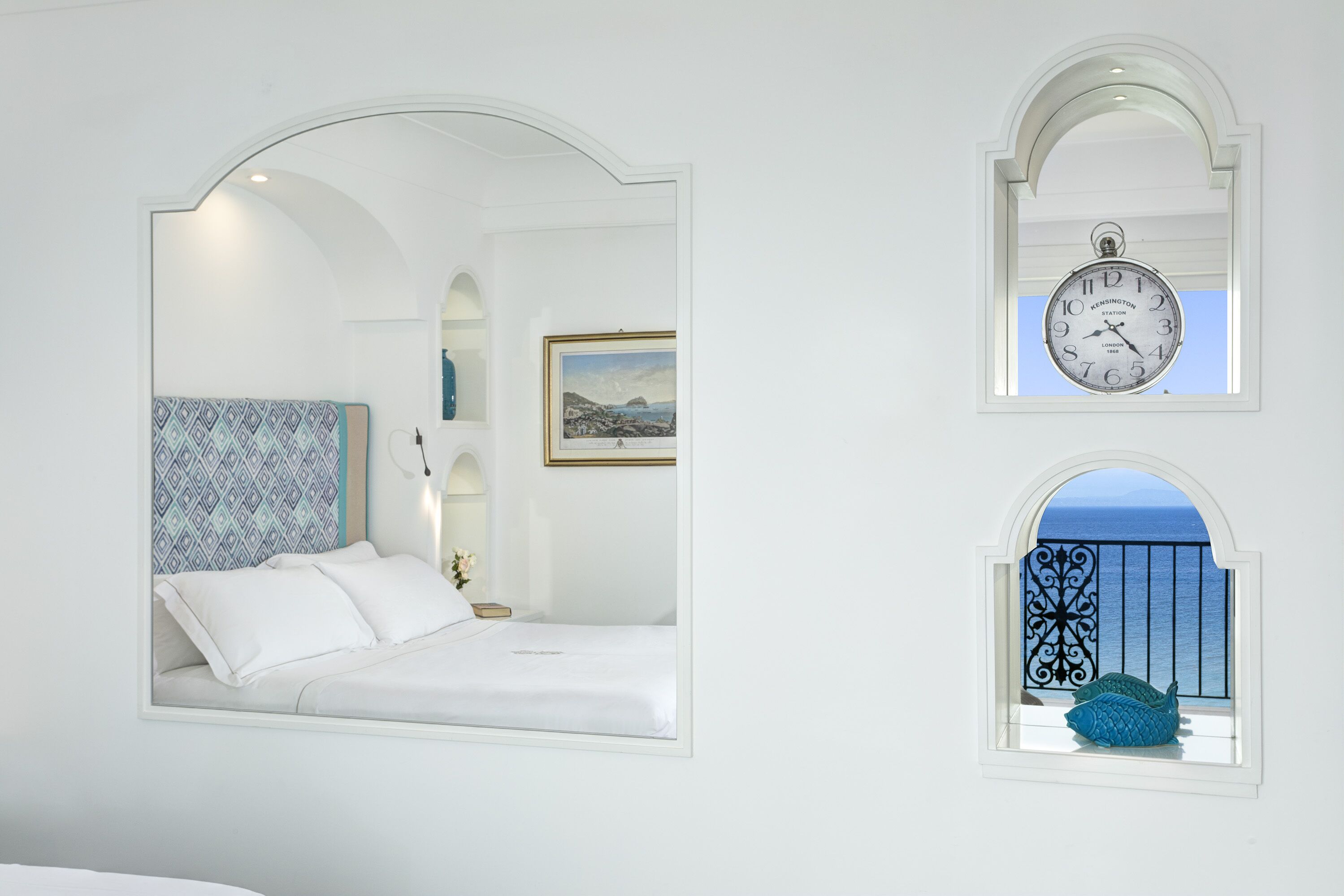 Un dormitorio con cama, un reloj y vista al mar a través de una ventana.