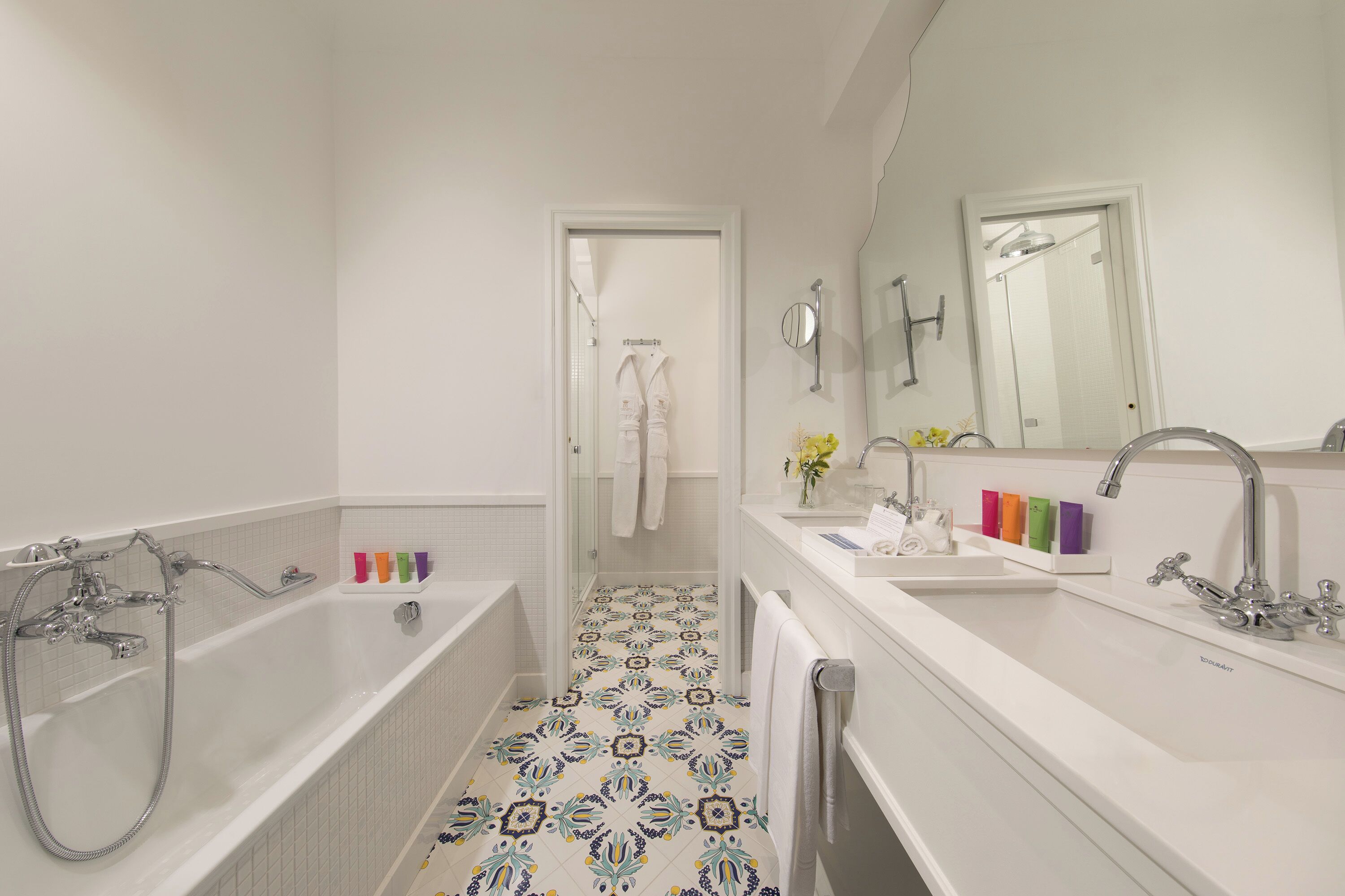 Ein modernes Badezimmer mit Badewanne, Dusche und Waschbecken. Handtücher hängen an der Wand und über dem Waschbecken befindet sich ein Spiegel.