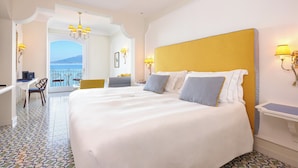 Une chambre d’hôtel avec un grand lit, un bureau et une vue sur la mer.