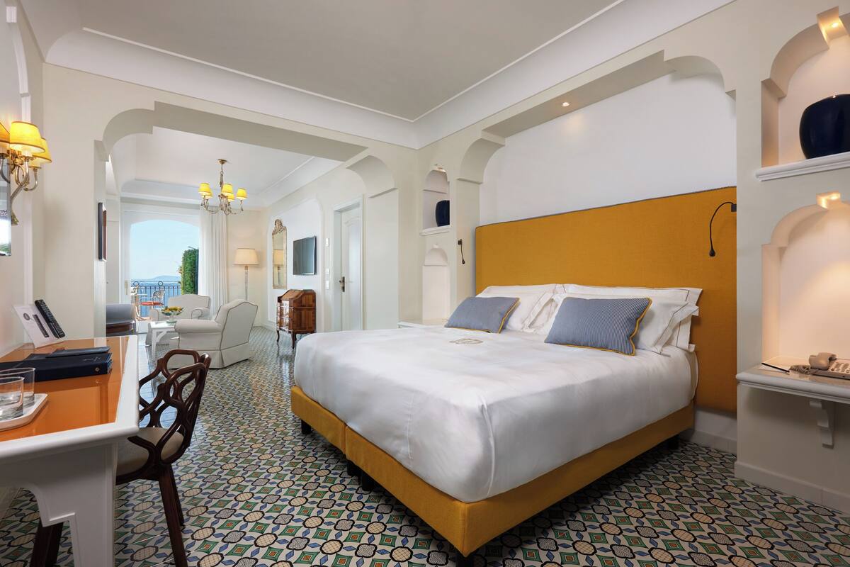 Een hotelkamer met een groot bed, een bureau met stoel en uitzicht op de omgeving.