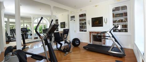 Un gimnasio en casa con cintas de correr, elípticas y una bicicleta estática.