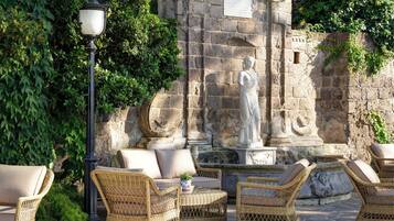 Wicker furniture, a stone wall, and a statue in an outdoor setting.