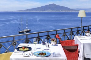 Een eettafel met uitzicht op zee en een berg op de achtergrond.