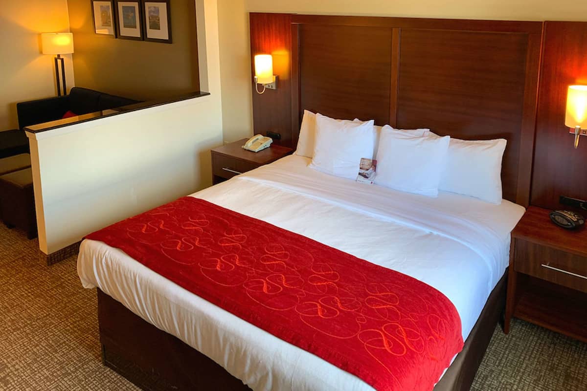 A hotel room with a large bed, a desk, and two bedside lamps.