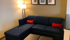 A sectional sofa with red cushions, a floor lamp, and framed pictures on the wall.