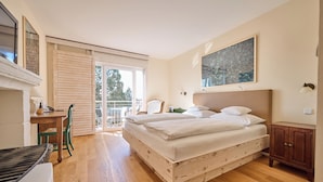 Een slaapkamer met een houten bed, een bureau, een stoel en uitzicht op de omgeving.