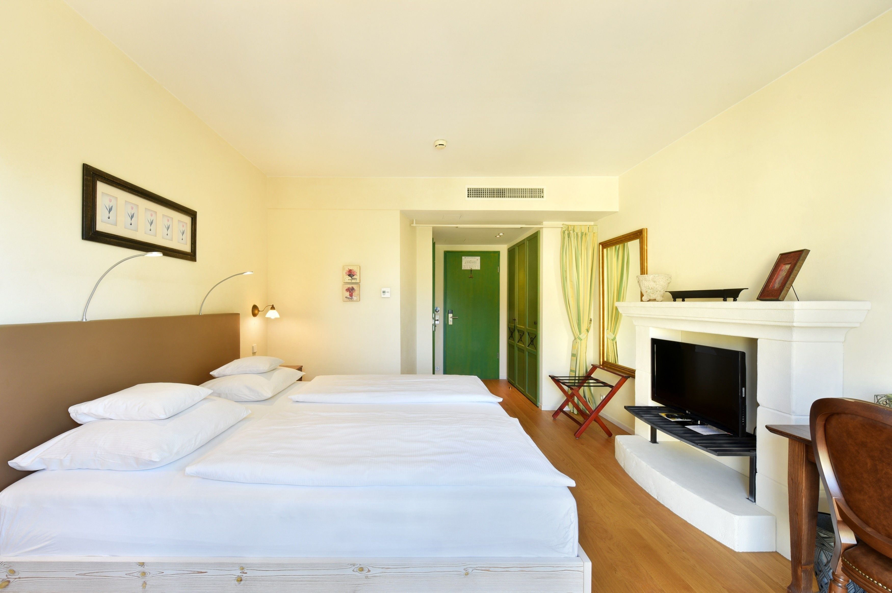 A hotel room with a large bed, a television, and a fireplace.