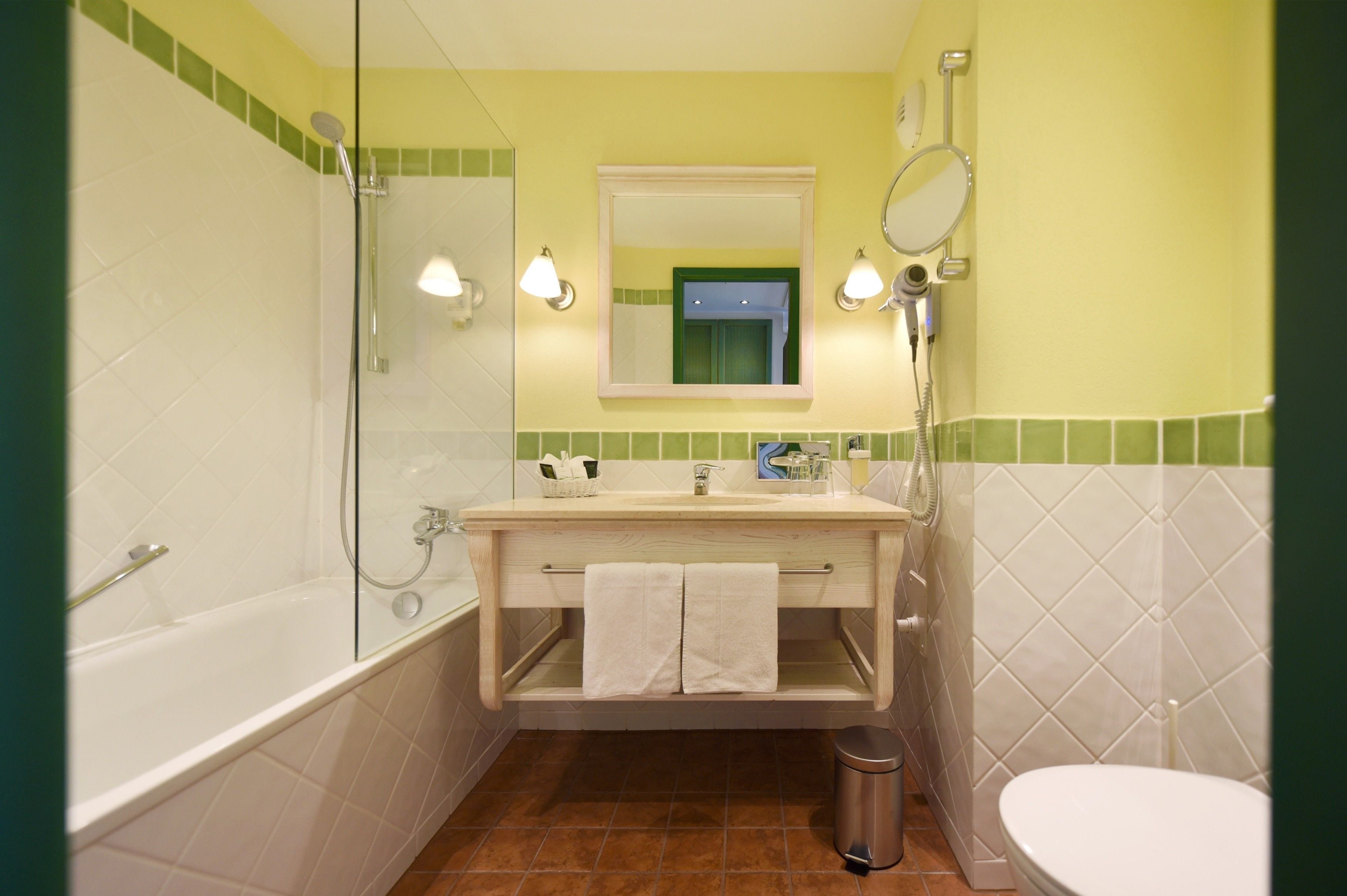 A bathroom with a bathtub, a sink, a mirror, and a toilet.