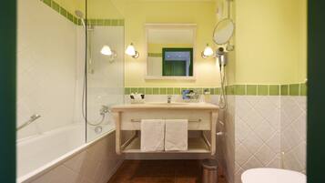 A bathroom with a bathtub, a sink, a mirror, and a toilet.