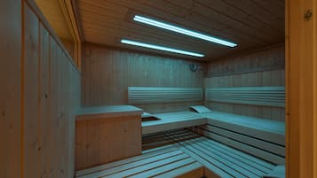 Una sauna con bancos de madera y paredes de madera, con techo de luces fluorescentes.