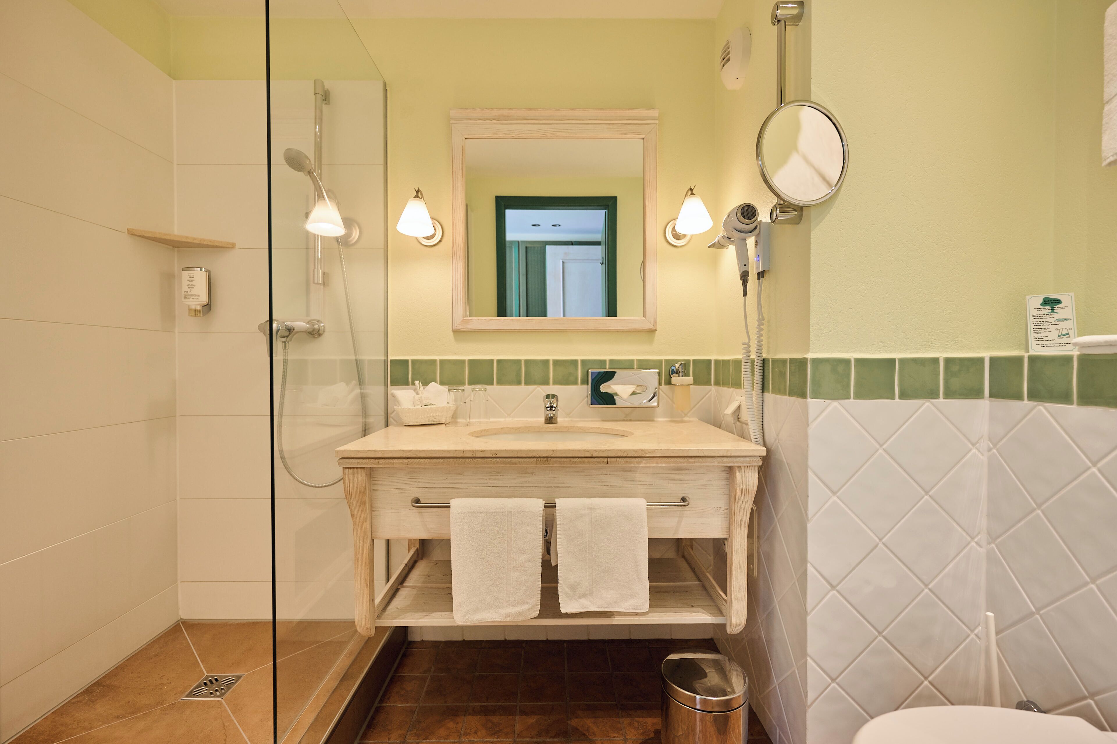 Een badkamer met een douchecabine van glas, een wastafel met spiegel en een toilet.