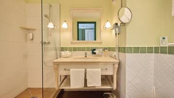 Een badkamer met een douchecabine van glas, een wastafel met spiegel en een toilet.