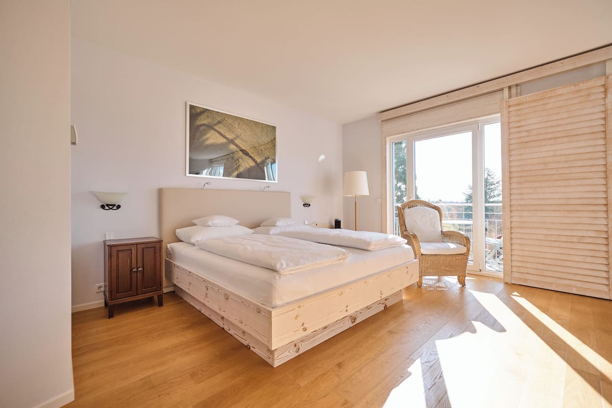 A bedroom with a large bed, a chair, a cabinet, and a window.