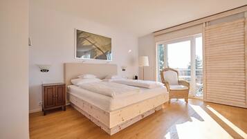 Une chambre avec un grand lit, une chaise, une armoire et une fenêtre.