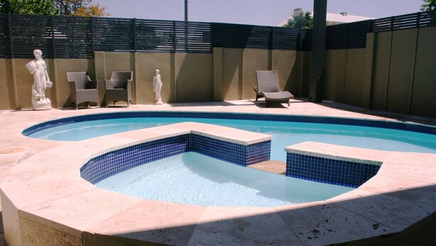 A swimming pool with a unique design, surrounded by lounge chairs and a statue. - Noah's Mid City Motor Inn (Muswellbrook)