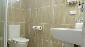 Un baño con azulejos color beige, inodoro, lavamanos y ventana.