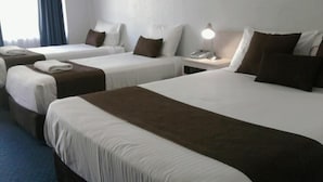 A hotel room with three single beds, each with a brown headboard, white bedding, and a bedside lamp. - Noah's Mid City Motor Inn (Muswellbrook)