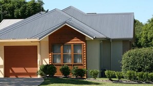 A single-story house with a garage, a sloped metal roof, and a front porch with a window. - Noah's Mid City Motor Inn (Muswellbrook)